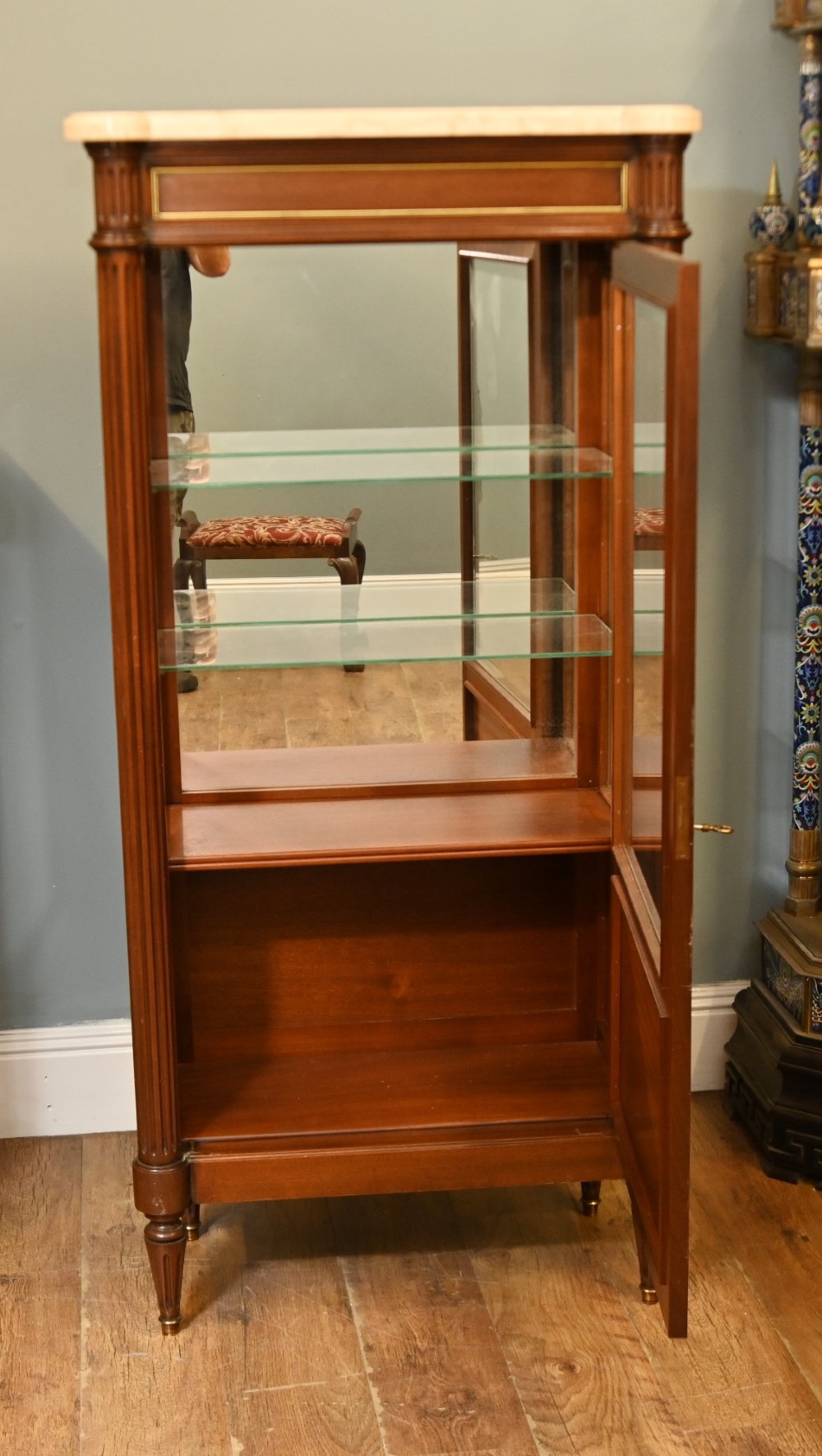 A French Directoire style mahogany vitrine cabinet featuring a single glazed door, fluted corner pilasters, brass line inlays, tapered turned feet, and a marble top surface. View VI