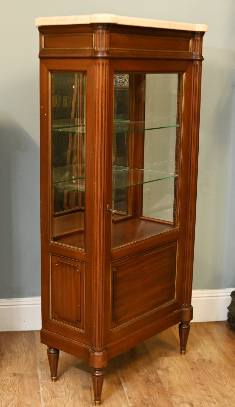 A French Directoire style mahogany vitrine cabinet featuring a single glazed door, fluted corner pilasters, brass line inlays, tapered turned feet, and a marble top surface. View VIII