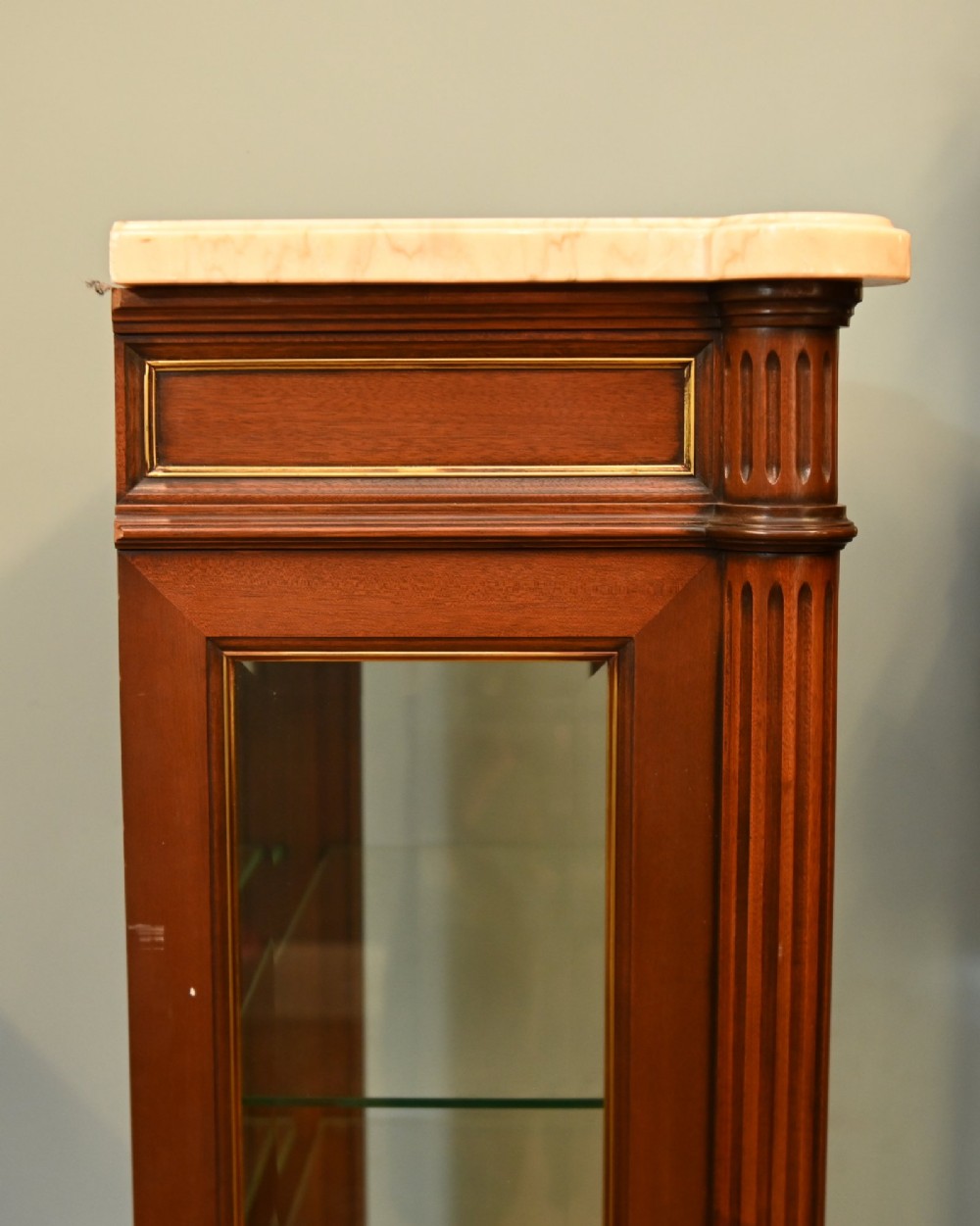 A French Directoire style mahogany vitrine cabinet featuring a single glazed door, fluted corner pilasters, brass line inlays, tapered turned feet, and a marble top surface. View X