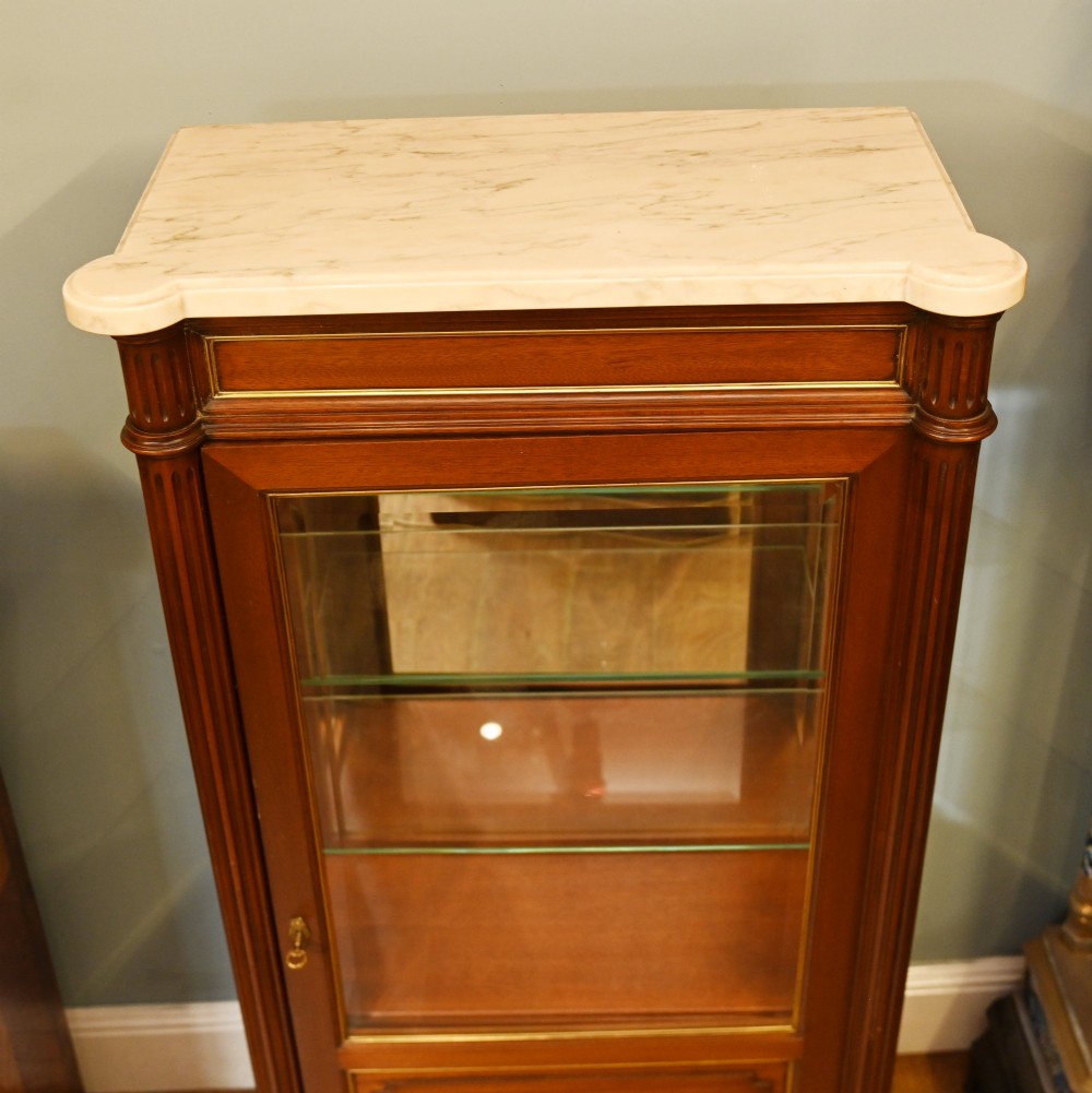 A French Directoire style mahogany vitrine cabinet featuring a single glazed door, fluted corner pilasters, brass line inlays, tapered turned feet, and a marble top surface. View XII