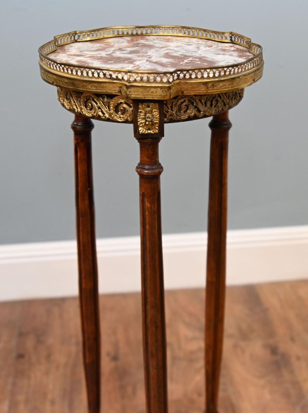 A French Louis XVI style pedestal stand featuring a circular marble top with a pierced brass gallery, supported by three fluted legs and a lower tier. View IV