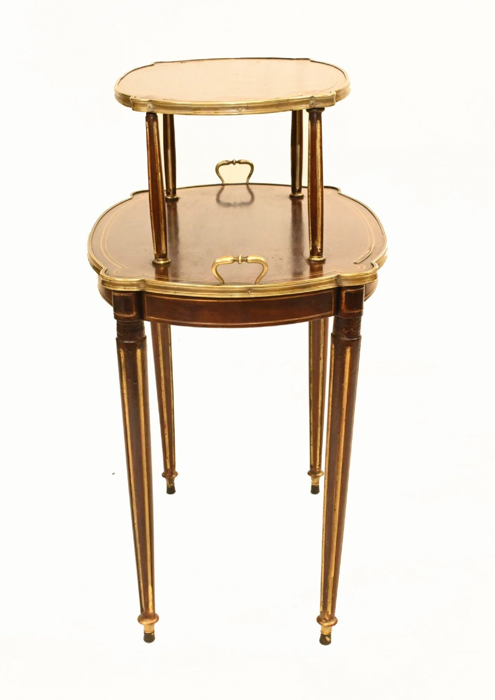 A two-tiered mahogany side table featuring shaped oval tops edged with brass galleries, slender turned legs, and brass side handles on the lower tier. View II