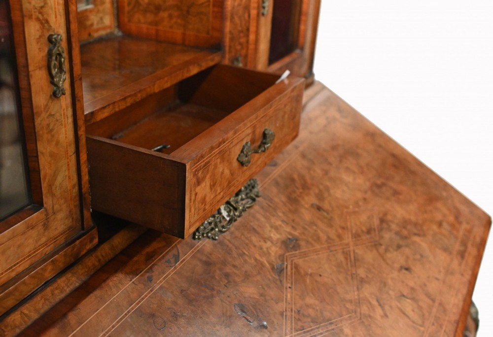 A 19th-century French walnut bonheur du jour desk featuring cabriole legs, a slant-front writing slope, and an upper superstructure with small glazed cabinets framing a central arched mirror. View X