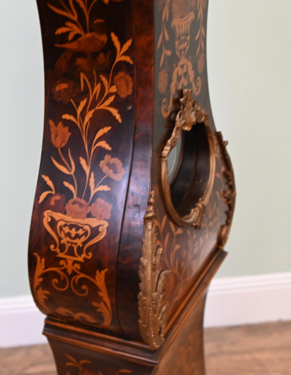 A tall French longcase clock featuring dark brown wood with elaborate floral marquetry inlay, gilt brass mounts, and a circular white enamel dial. View IV