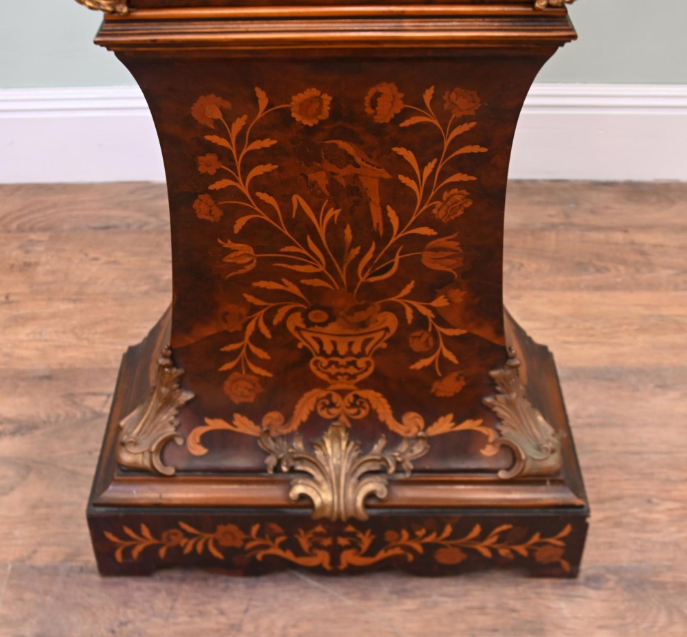 A tall French longcase clock featuring dark brown wood with elaborate floral marquetry inlay, gilt brass mounts, and a circular white enamel dial. View V