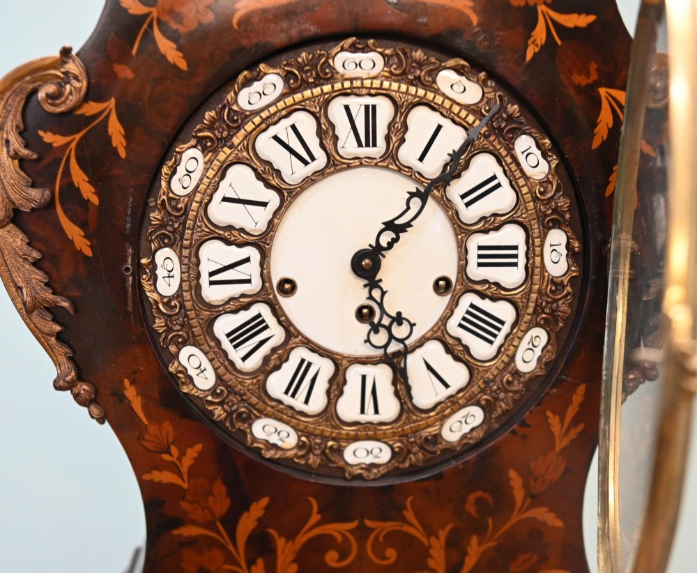 A tall French longcase clock featuring dark brown wood with elaborate floral marquetry inlay, gilt brass mounts, and a circular white enamel dial. View VI