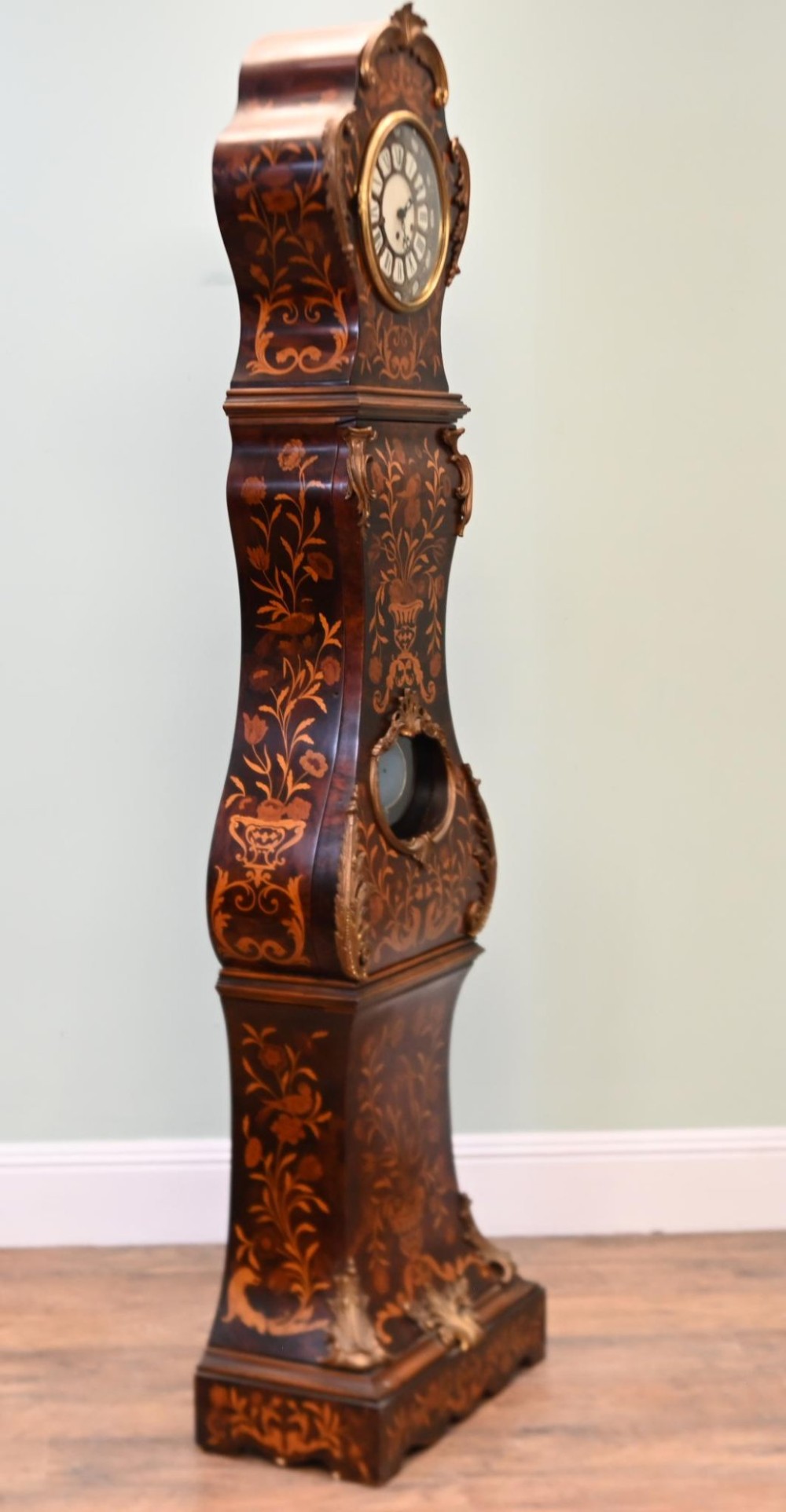A tall French longcase clock featuring dark brown wood with elaborate floral marquetry inlay, gilt brass mounts, and a circular white enamel dial. View X