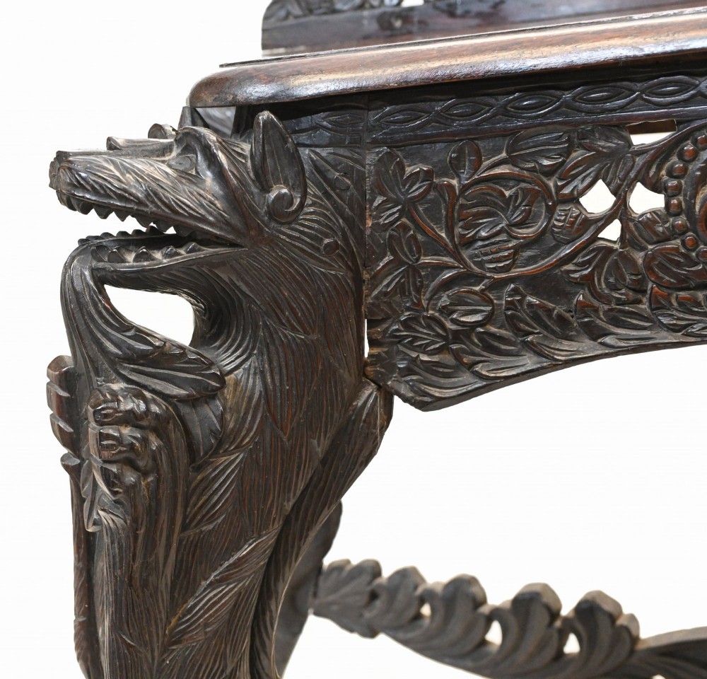 A late 19th-century Burmese dark teak console table featuring intricately pierced foliate carvings on the gallery back, skirt, and cross-stretcher, supported by legs carved as mythical figures. View III