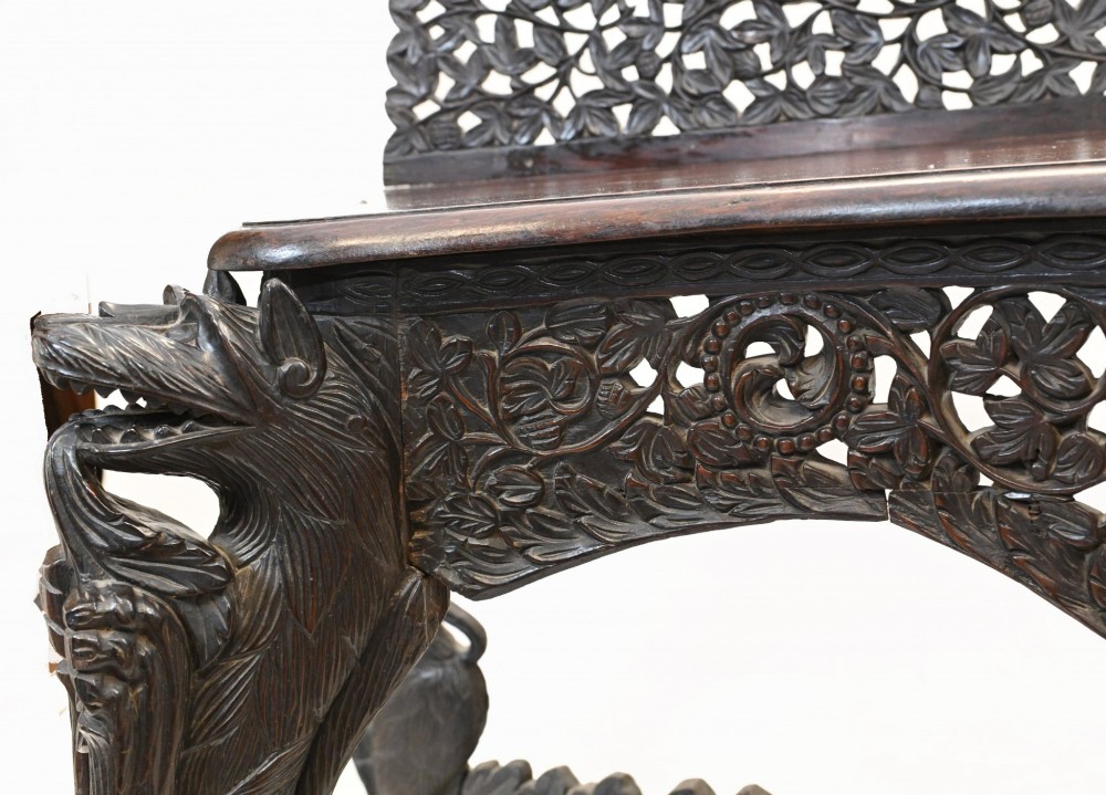 A late 19th-century Burmese dark teak console table featuring intricately pierced foliate carvings on the gallery back, skirt, and cross-stretcher, supported by legs carved as mythical figures. View VI