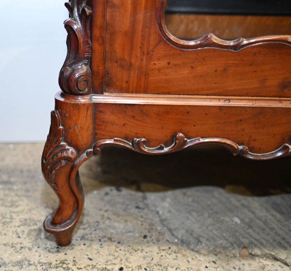 An antique French mahogany glazed vitrine cabinet featuring ornate cresting carvings, glass shelves, and carved cabriole legs. View III