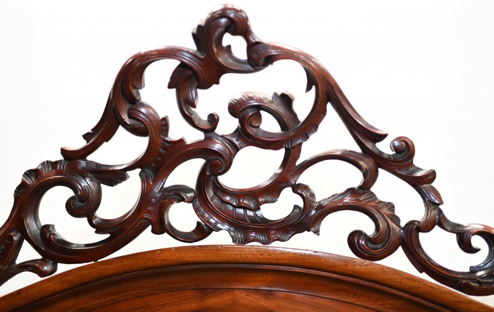 An antique French mahogany glazed vitrine cabinet featuring ornate cresting carvings, glass shelves, and carved cabriole legs. View V