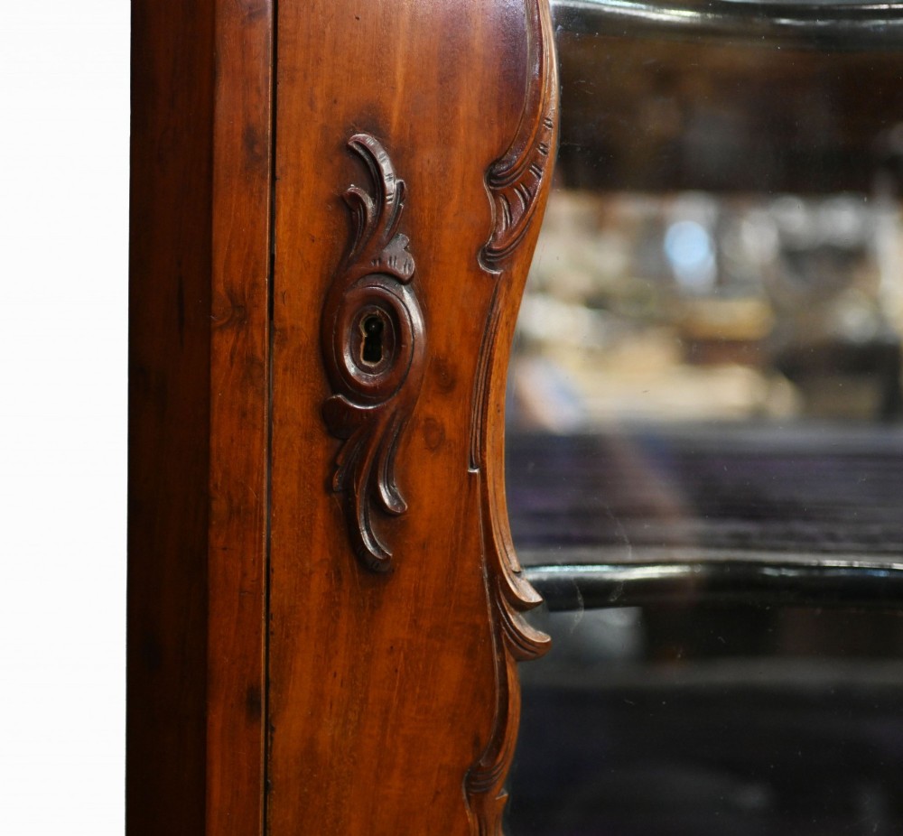 An antique French mahogany glazed vitrine cabinet featuring ornate cresting carvings, glass shelves, and carved cabriole legs. View X