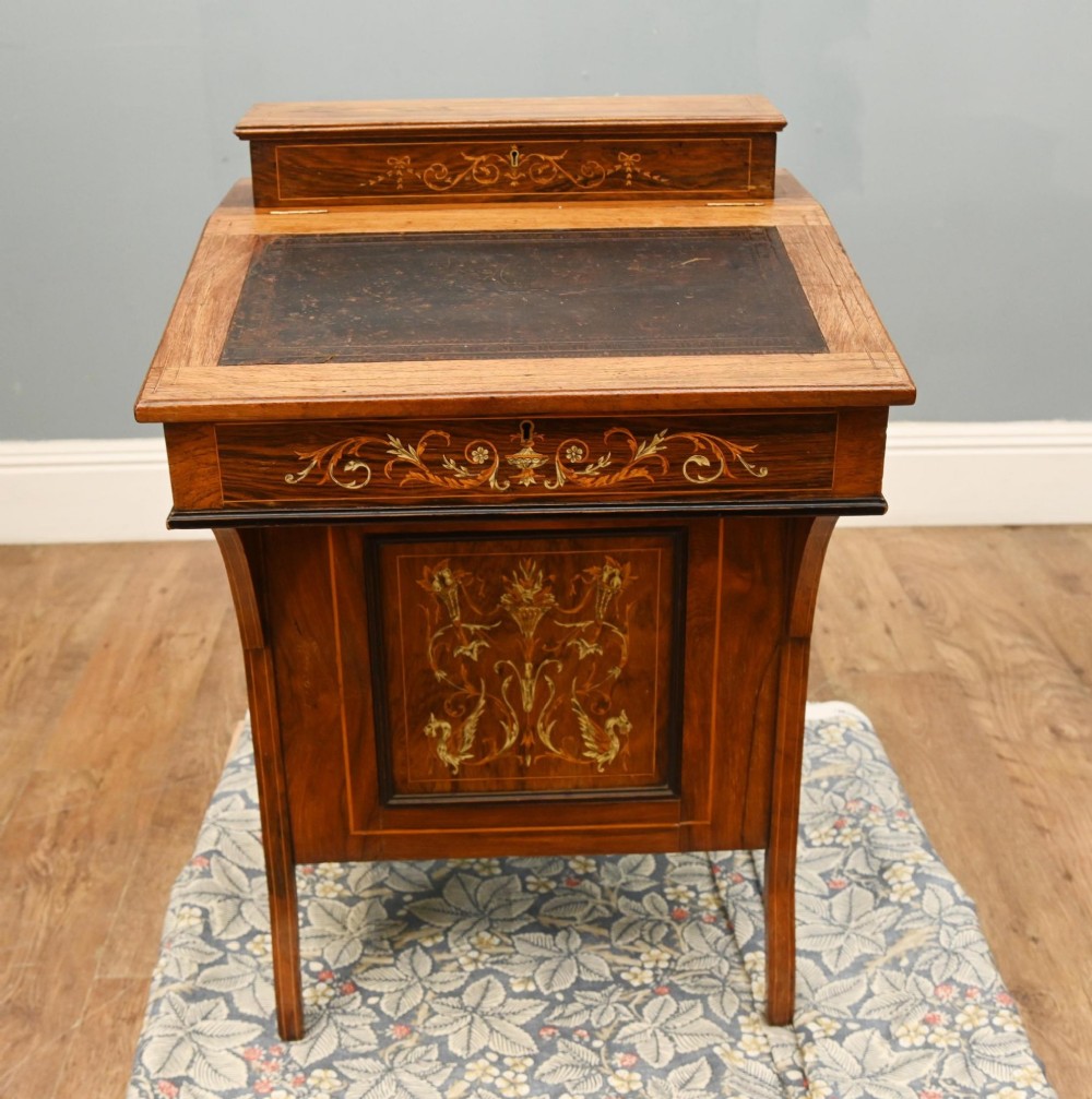 A late Victorian Sheraton Revival davenport desk crafted from warm brown wood, featuring decorative marquetry inlay and a dark leather inset writing surface.