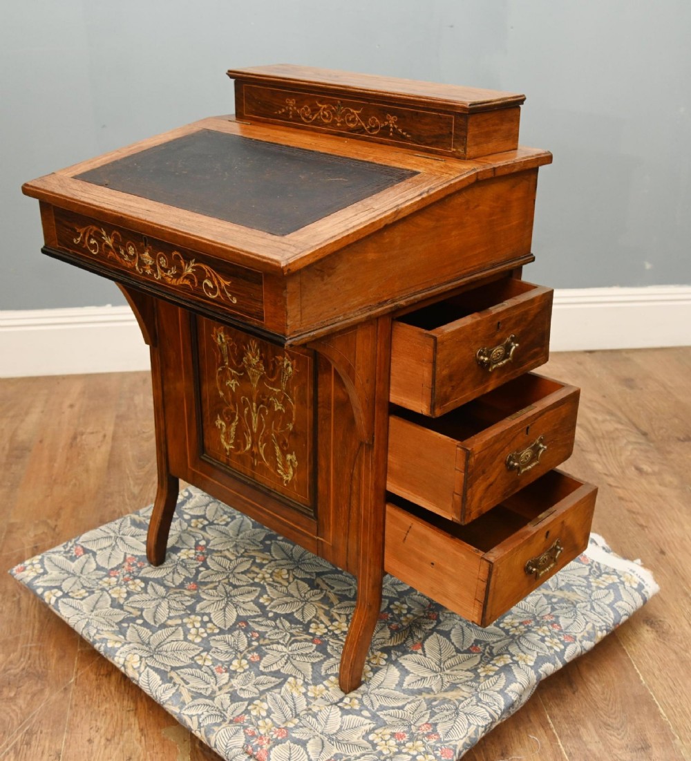 A late Victorian Sheraton Revival davenport desk crafted from warm brown wood, featuring decorative marquetry inlay and a dark leather inset writing surface. View VII
