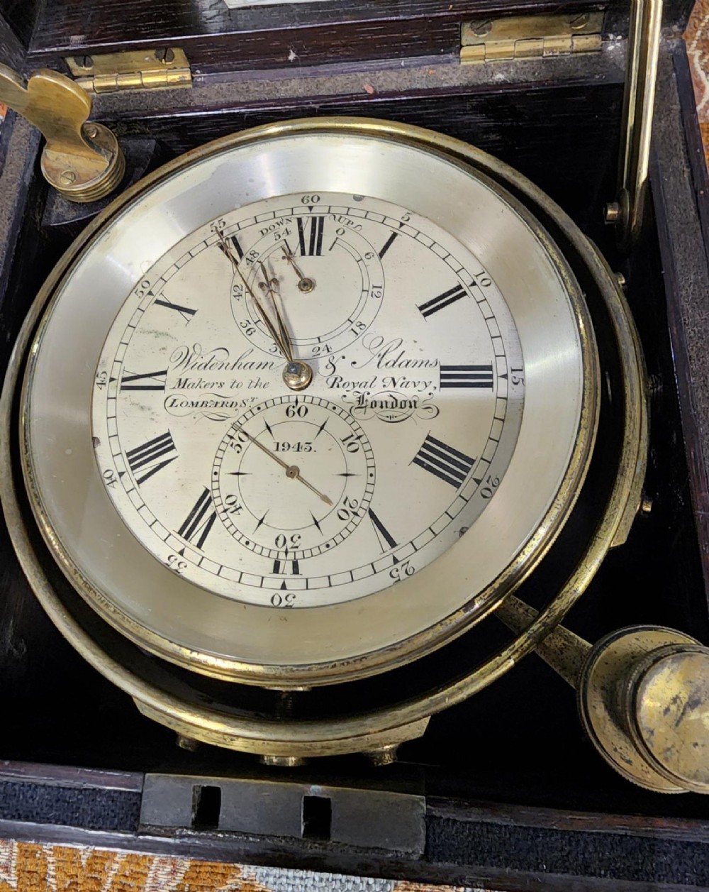 A Victorian brass marine chronometer mounted inside a brass-bound dark mahogany box with a printed manufacturer label. View VI