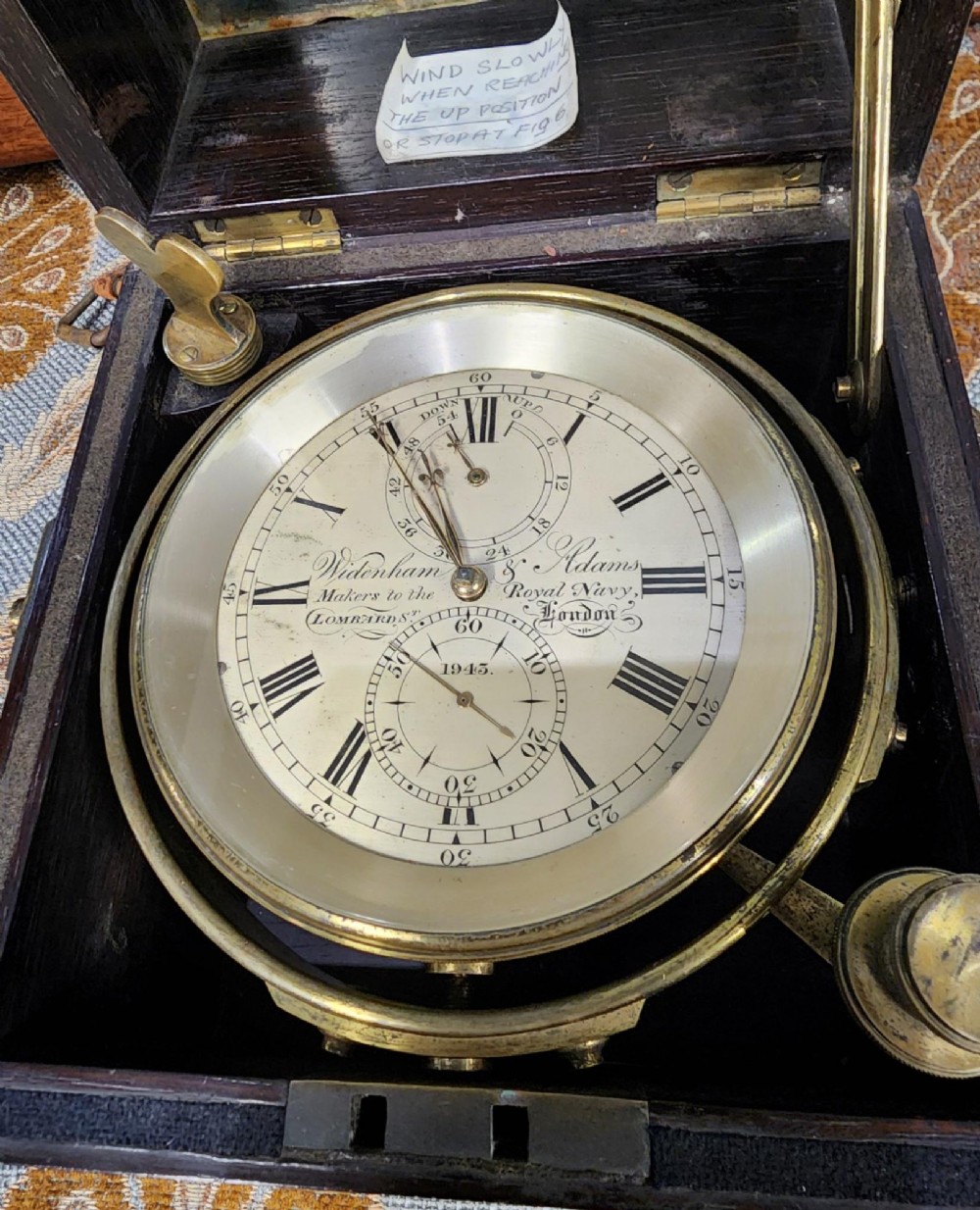 A Victorian brass marine chronometer mounted inside a brass-bound dark mahogany box with a printed manufacturer label. View XI