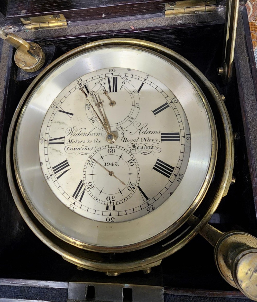 A Victorian brass marine chronometer mounted inside a brass-bound dark mahogany box with a printed manufacturer label. View XII