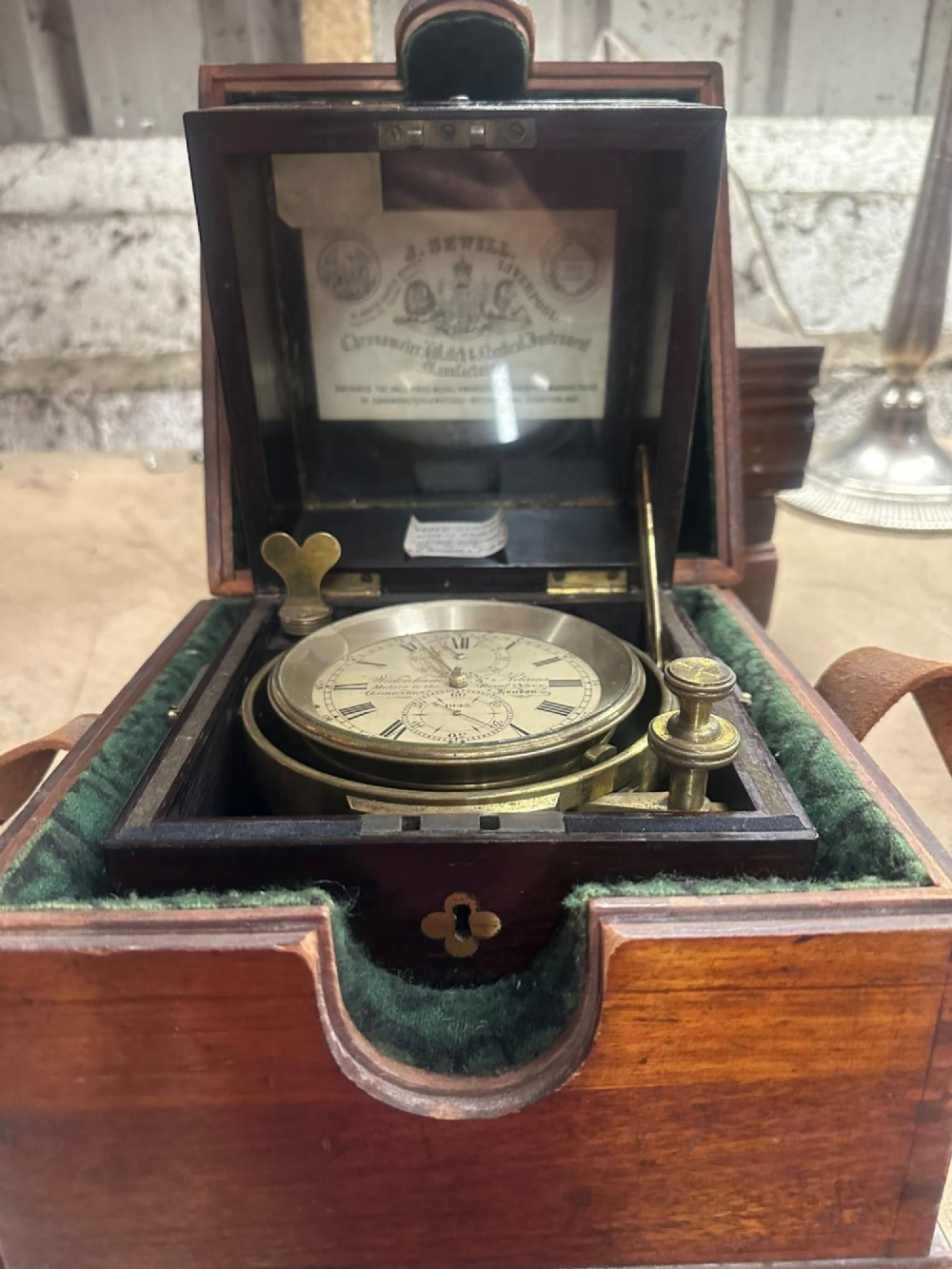 A Victorian brass marine chronometer mounted inside a brass-bound dark mahogany box with a printed manufacturer label. View XV
