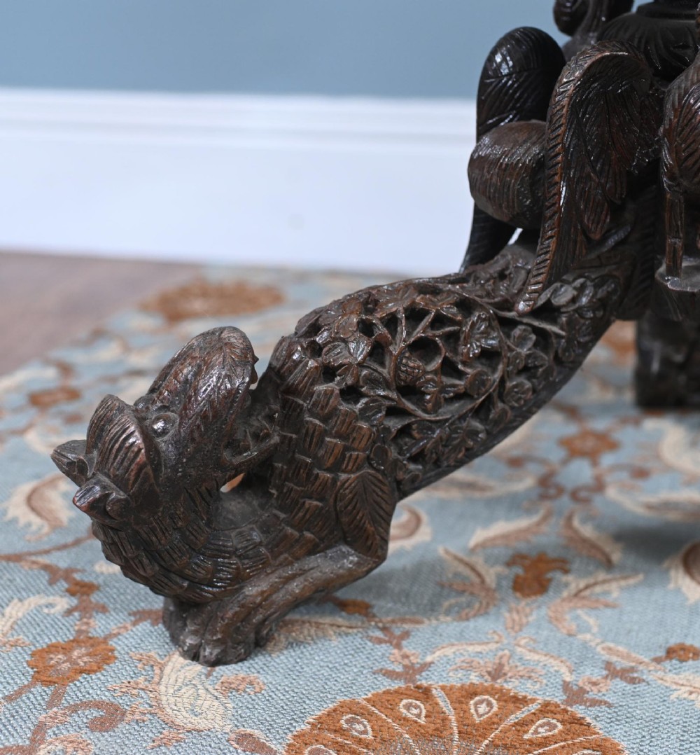 An antique dark hardwood Burmese side table with intricate pierced foliage carving around the circular top and a carved tripod base featuring mythological figure feet. View VIII