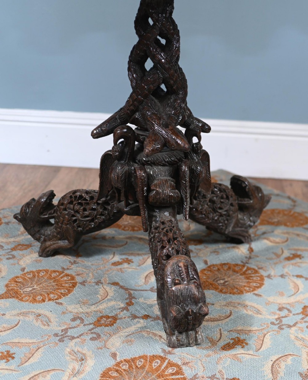 An antique dark hardwood Burmese side table with intricate pierced foliage carving around the circular top and a carved tripod base featuring mythological figure feet. View IX