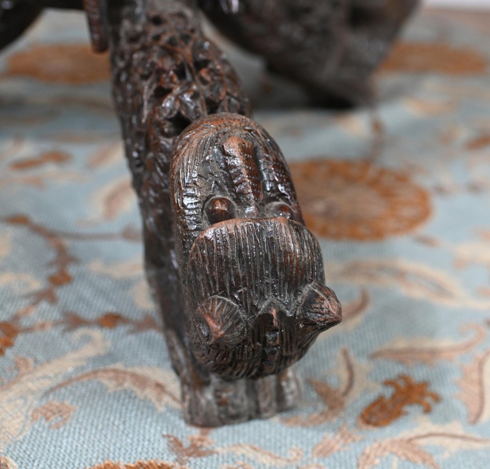 An antique dark hardwood Burmese side table with intricate pierced foliage carving around the circular top and a carved tripod base featuring mythological figure feet. View X