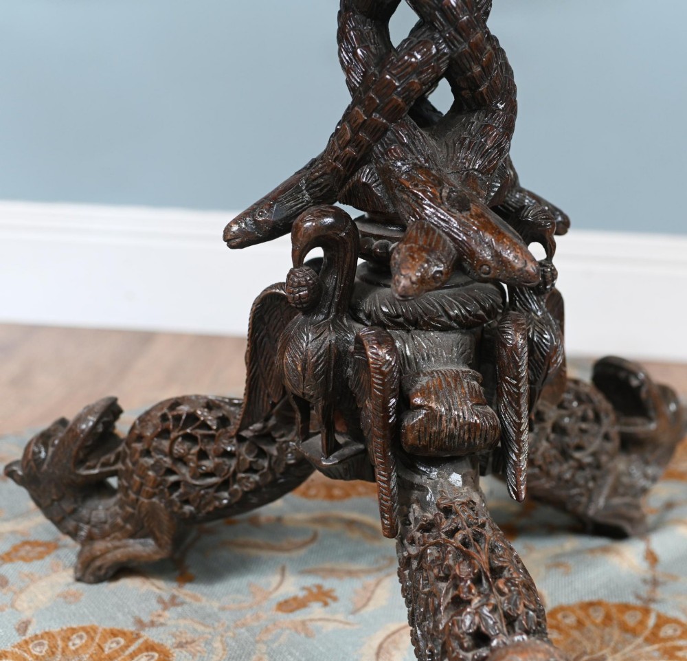 An antique dark hardwood Burmese side table with intricate pierced foliage carving around the circular top and a carved tripod base featuring mythological figure feet. View XI