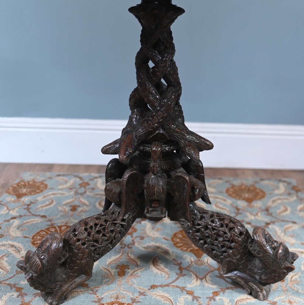 An antique dark hardwood Burmese side table with intricate pierced foliage carving around the circular top and a carved tripod base featuring mythological figure feet. View XIII