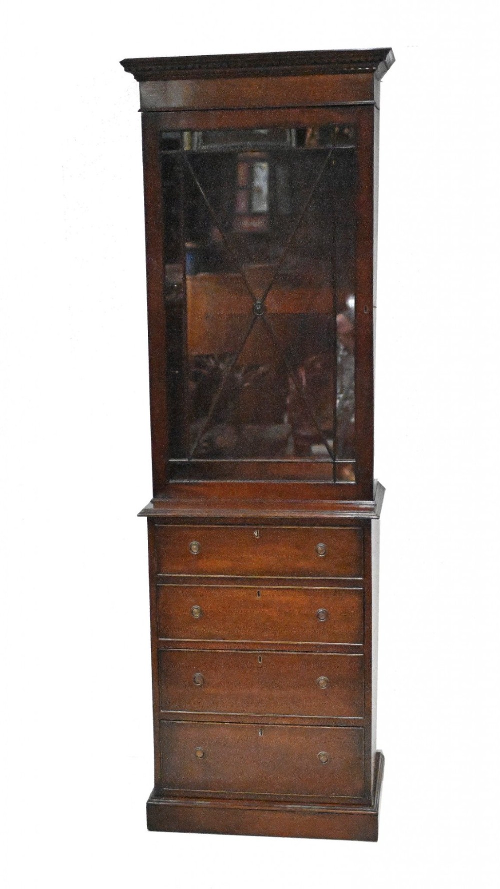 A tall Georgian mahogany glazed bookcase featuring an astragal glass upper cabinet set above four graduated drawers with brass pull knobs.