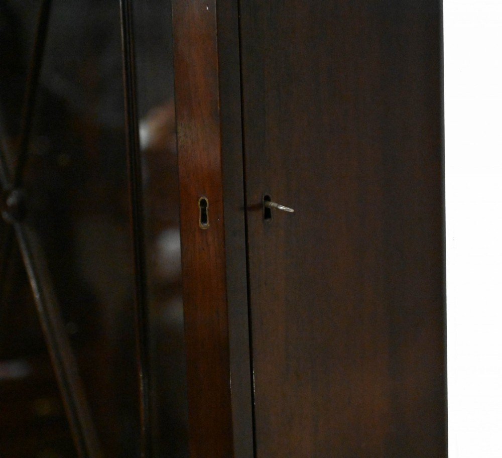 A tall Georgian mahogany glazed bookcase featuring an astragal glass upper cabinet set above four graduated drawers with brass pull knobs. View III