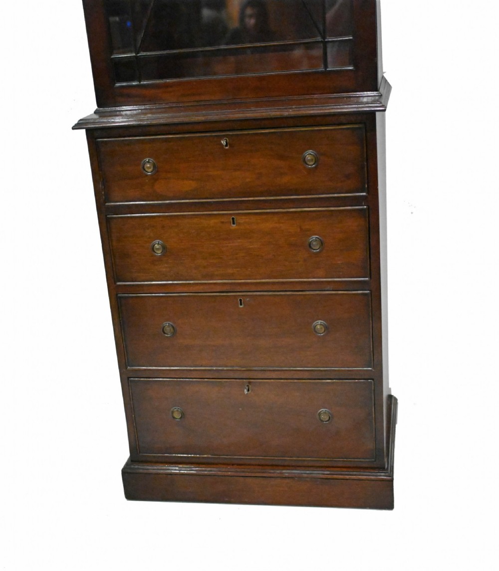 A tall Georgian mahogany glazed bookcase featuring an astragal glass upper cabinet set above four graduated drawers with brass pull knobs. View VI