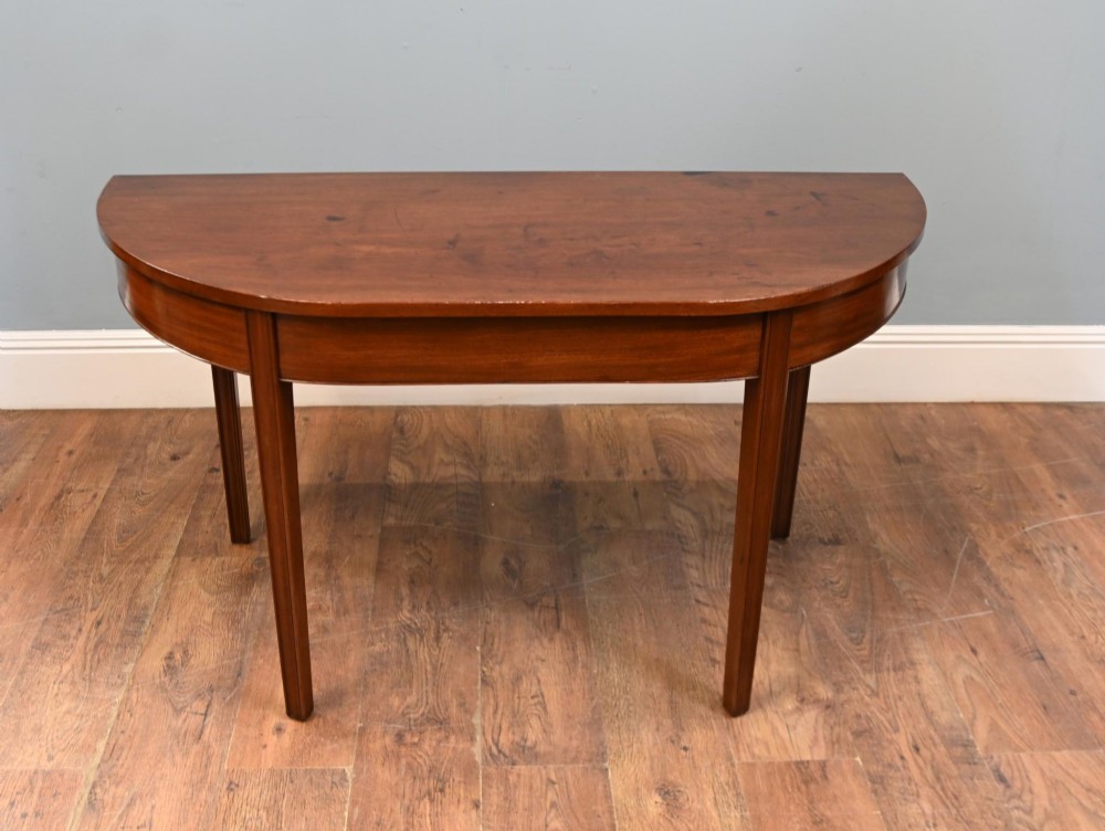 A pair of antique Georgian mahogany demi-lune console tables with semi-circular tops and straight tapered legs. View IV