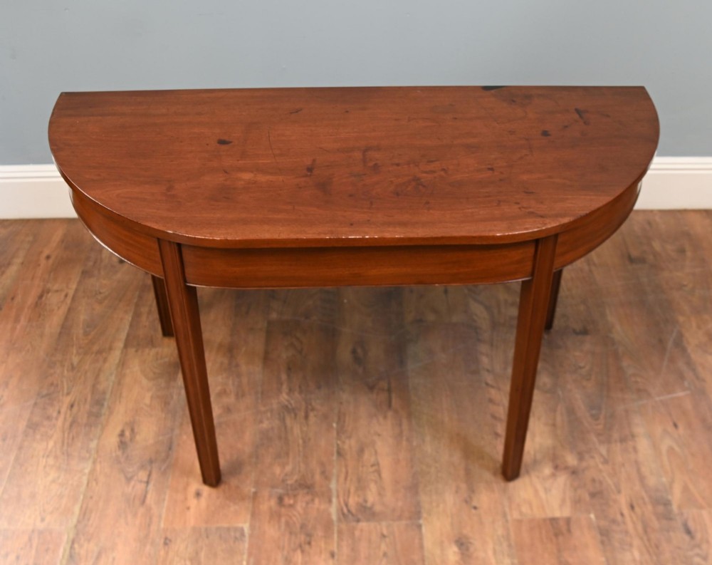 A pair of antique Georgian mahogany demi-lune console tables with semi-circular tops and straight tapered legs. View V