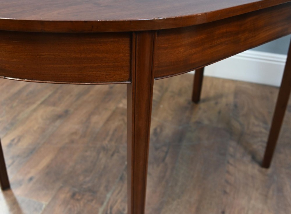 A pair of antique Georgian mahogany demi-lune console tables with semi-circular tops and straight tapered legs. View VII