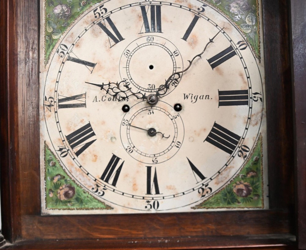 A Georgian mahogany longcase clock featuring a swan-neck pediment with three brass finials, a painted dial with Roman numerals, and a flame mahogany door. View III