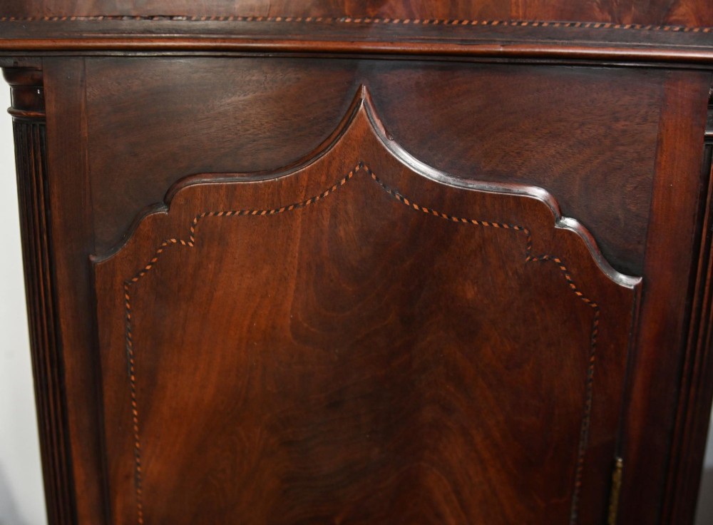 A Georgian mahogany longcase clock featuring a swan-neck pediment with three brass finials, a painted dial with Roman numerals, and a flame mahogany door. View X