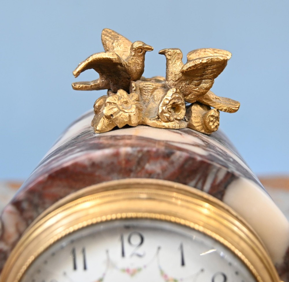 A late nineteenth-century French clock garniture set featuring a central portico clock in purple-veined white marble with gilt bronze mounts, flanked by two matching two-light candelabras. View VII