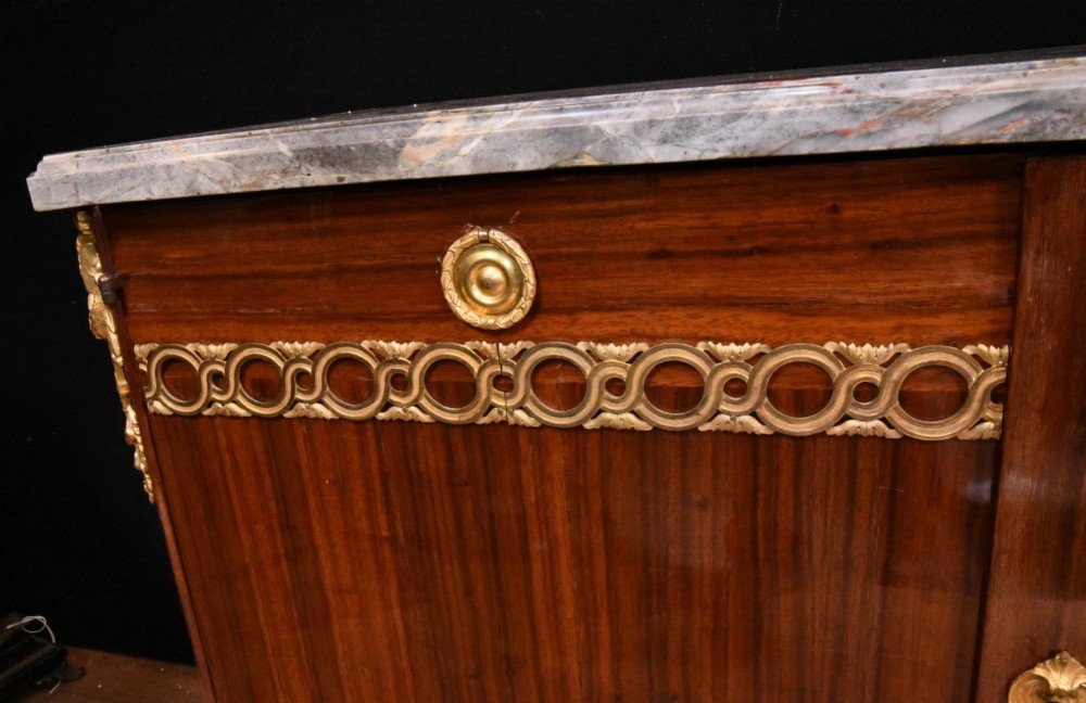 A French Empire style rosewood commode with a grey veined marble top, ornamental gilt bronze mounts, and square tapered legs with brass feet. View VI
