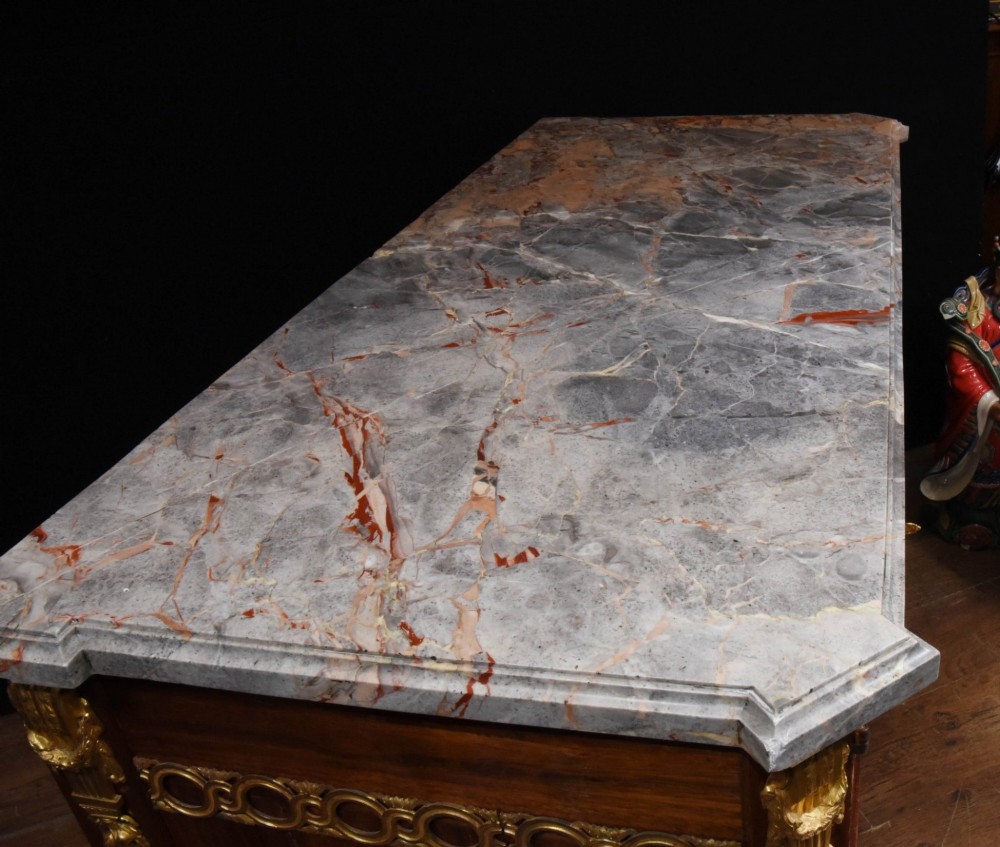 A French Empire style rosewood commode with a grey veined marble top, ornamental gilt bronze mounts, and square tapered legs with brass feet. View VII