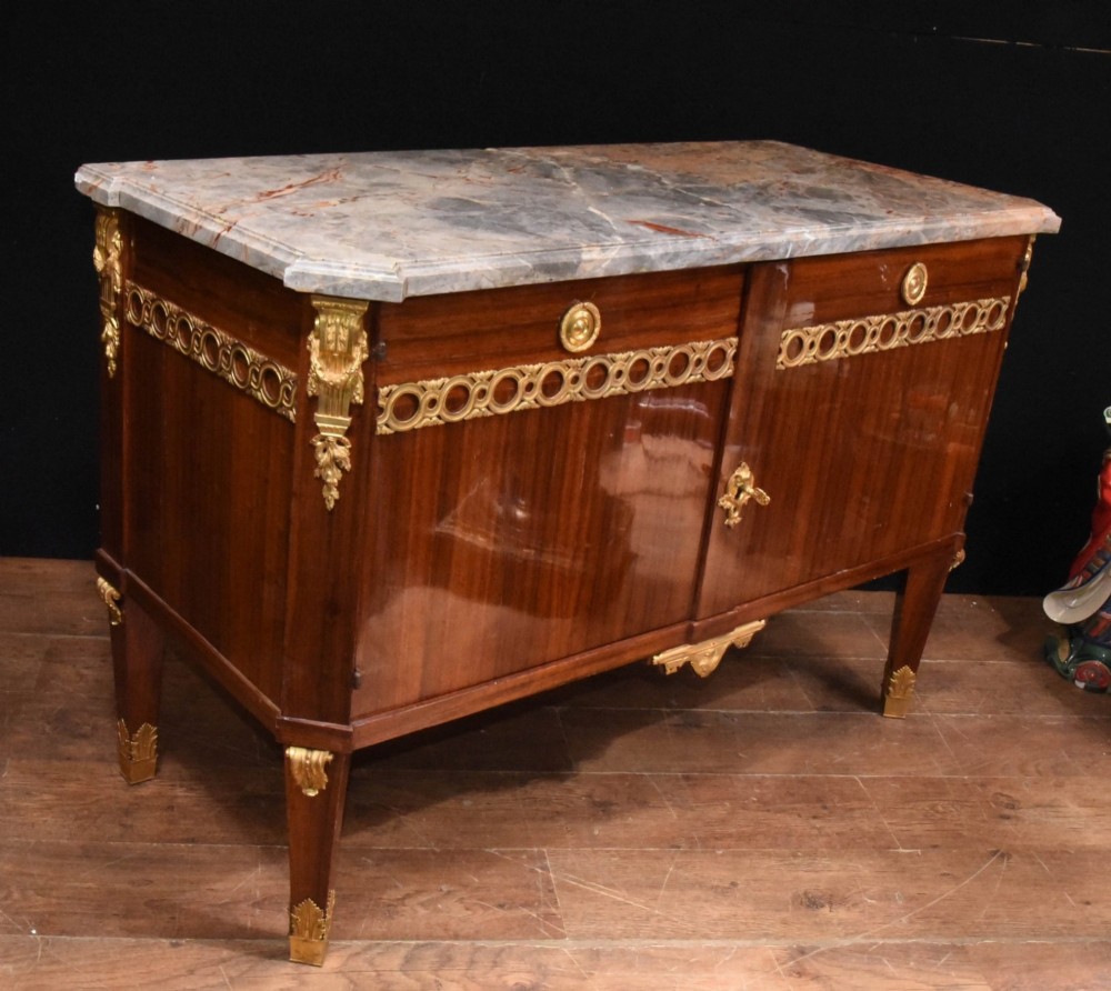 A French Empire style rosewood commode with a grey veined marble top, ornamental gilt bronze mounts, and square tapered legs with brass feet. View XI