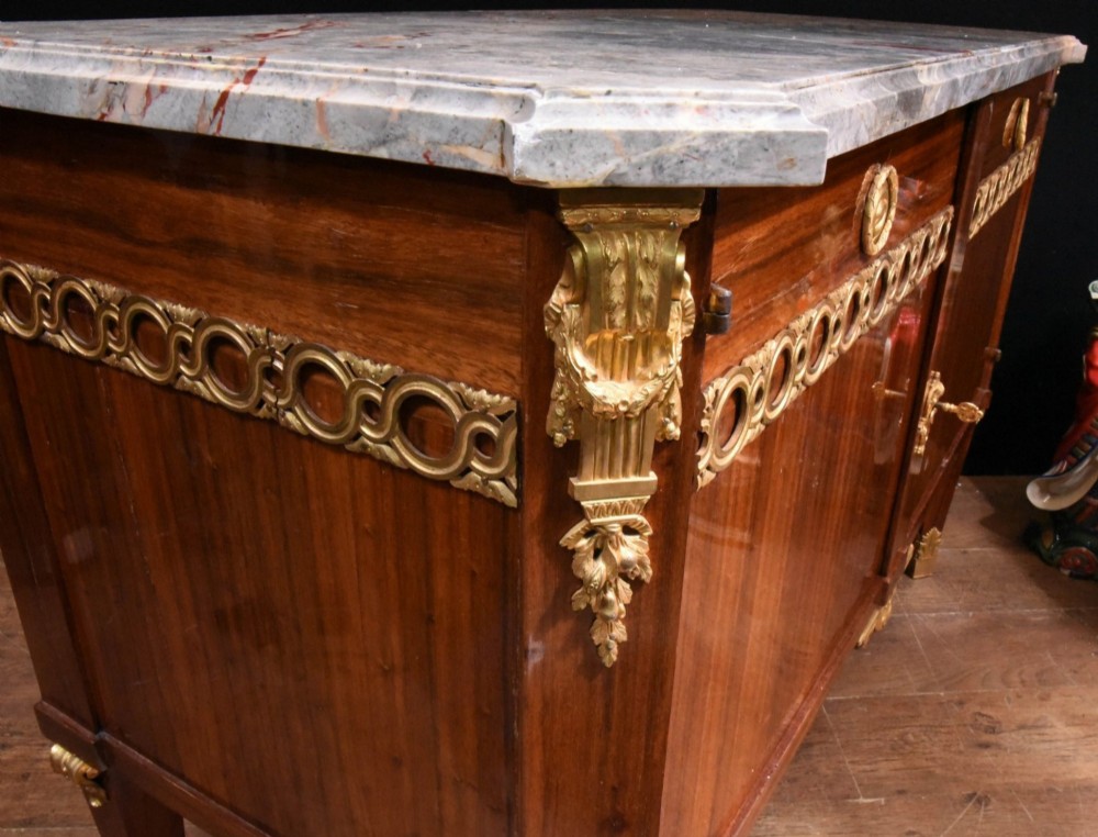 A French Empire style rosewood commode with a grey veined marble top, ornamental gilt bronze mounts, and square tapered legs with brass feet. View XII