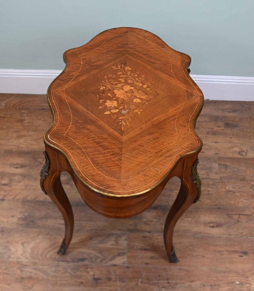 A French Louis XV style writing desk crafted from brown wood with a serpentine top, floral marquetry inlay, cabriole legs, and brass mounts. View II