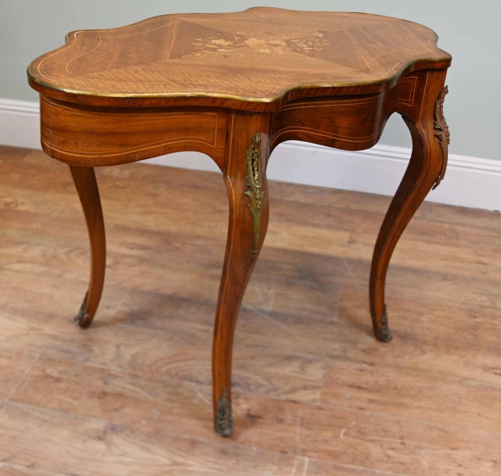 A French Louis XV style writing desk crafted from brown wood with a serpentine top, floral marquetry inlay, cabriole legs, and brass mounts. View III