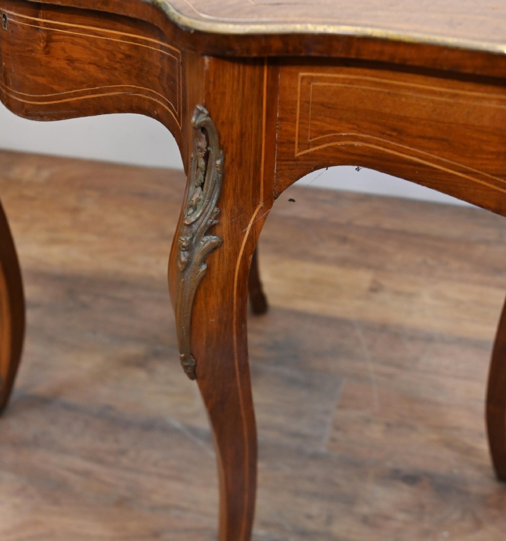 A French Louis XV style writing desk crafted from brown wood with a serpentine top, floral marquetry inlay, cabriole legs, and brass mounts. View IV