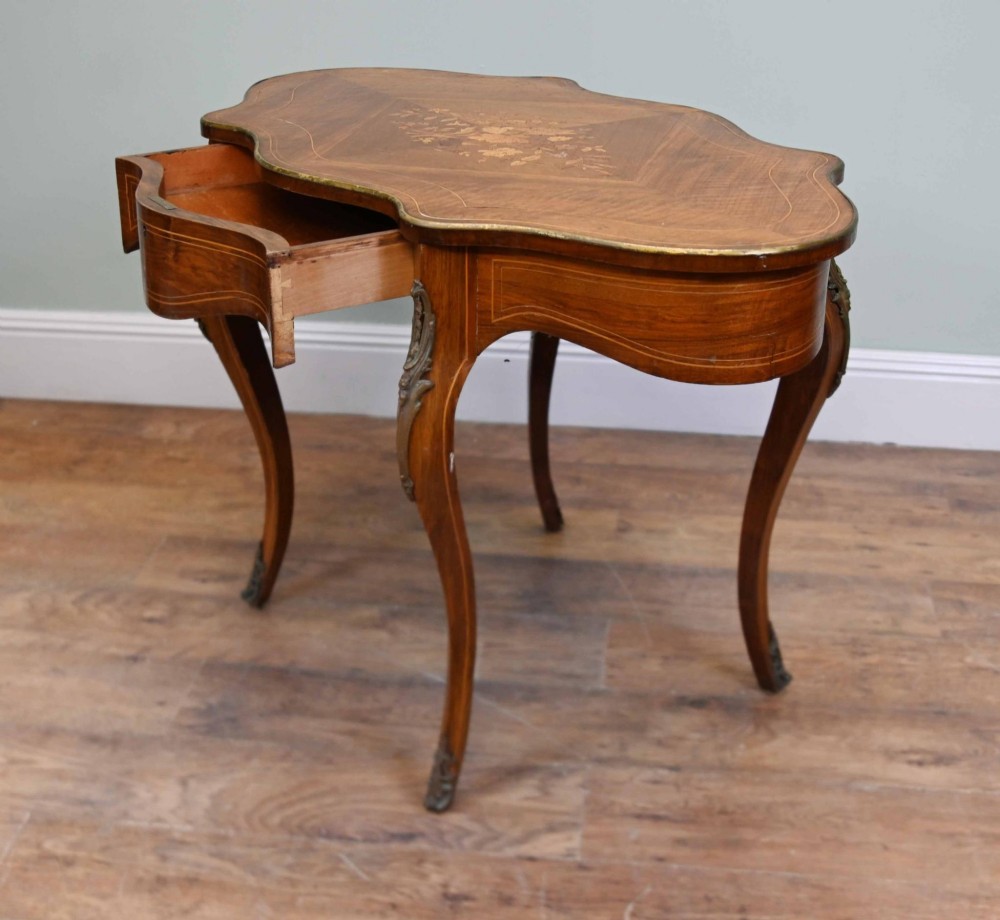 A French Louis XV style writing desk crafted from brown wood with a serpentine top, floral marquetry inlay, cabriole legs, and brass mounts. View VIII