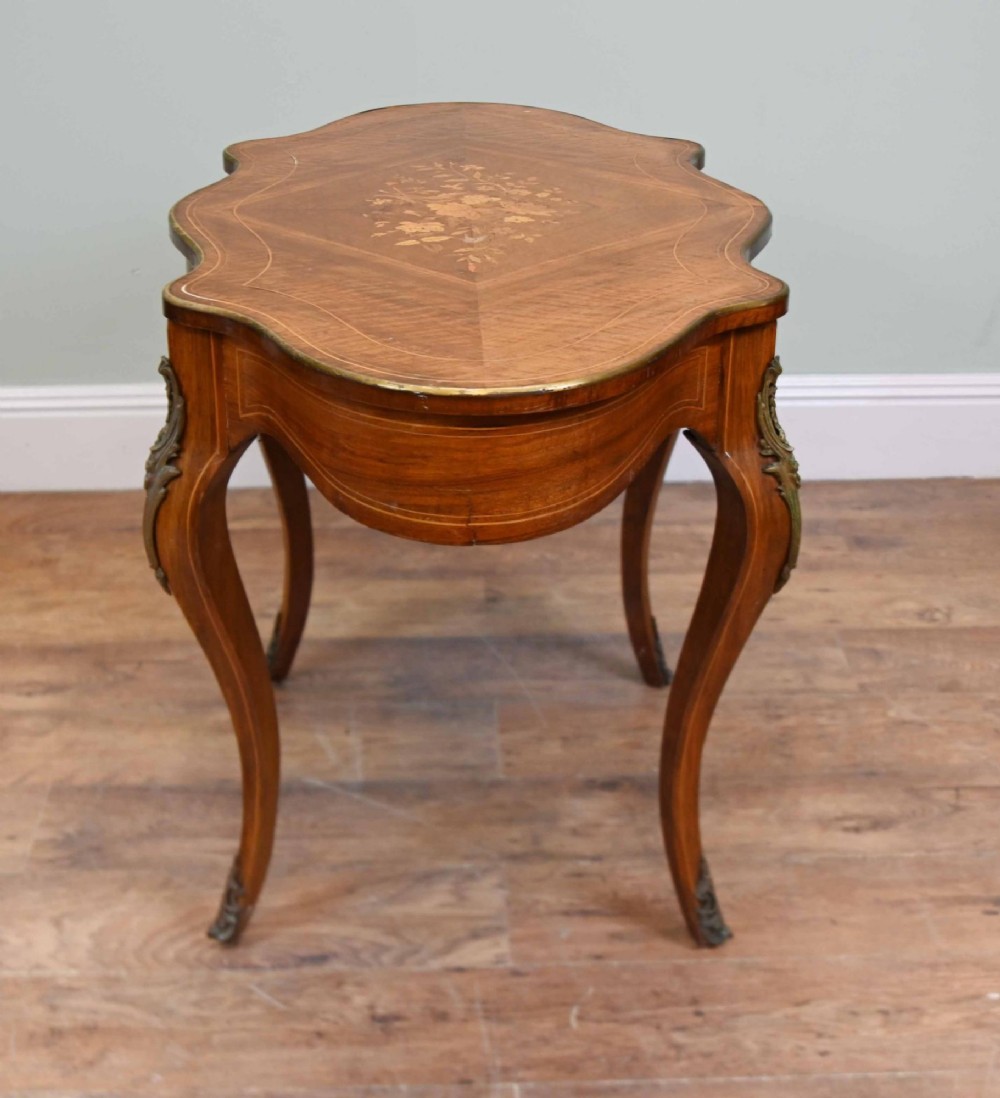 A French Louis XV style writing desk crafted from brown wood with a serpentine top, floral marquetry inlay, cabriole legs, and brass mounts. View XI