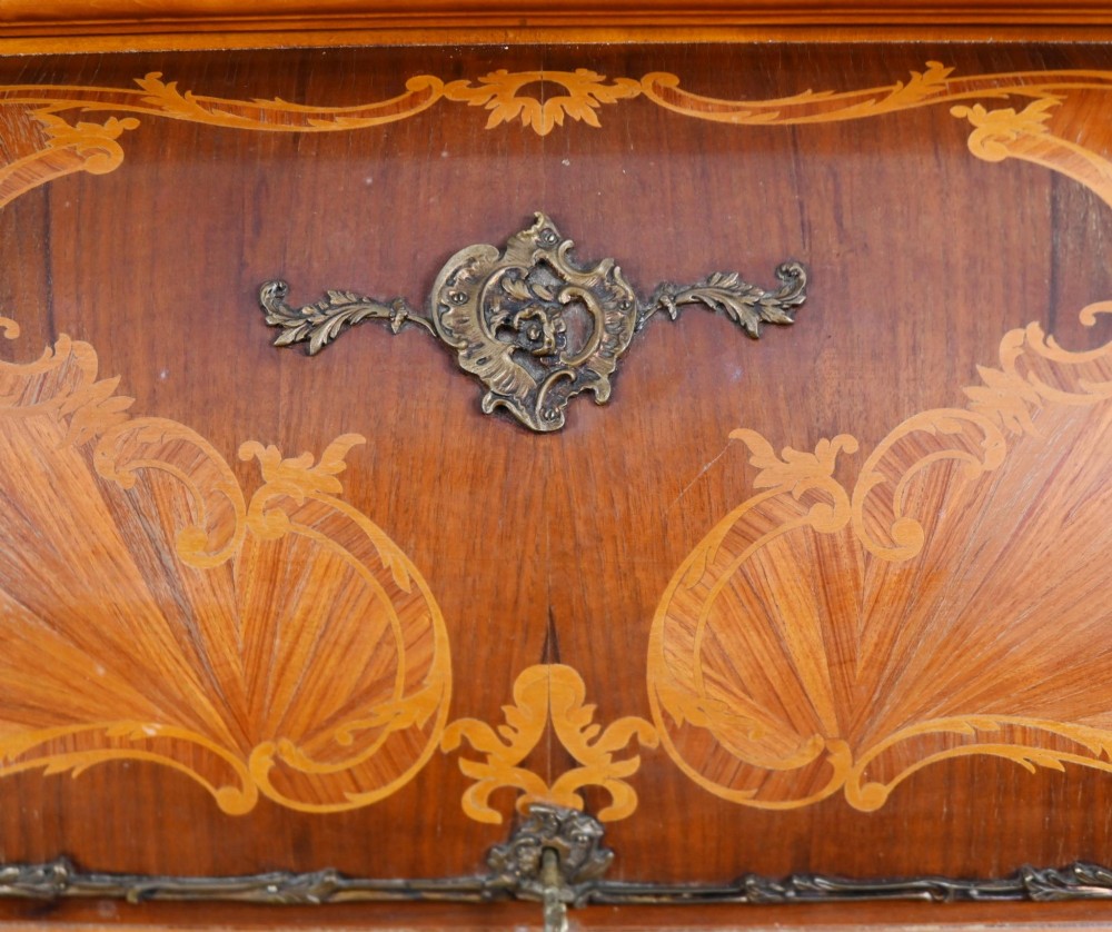 An antique French roll-top bureau featuring wood marquetry inlay, decorative brass mounts, cabriole legs, and drawers. View VI