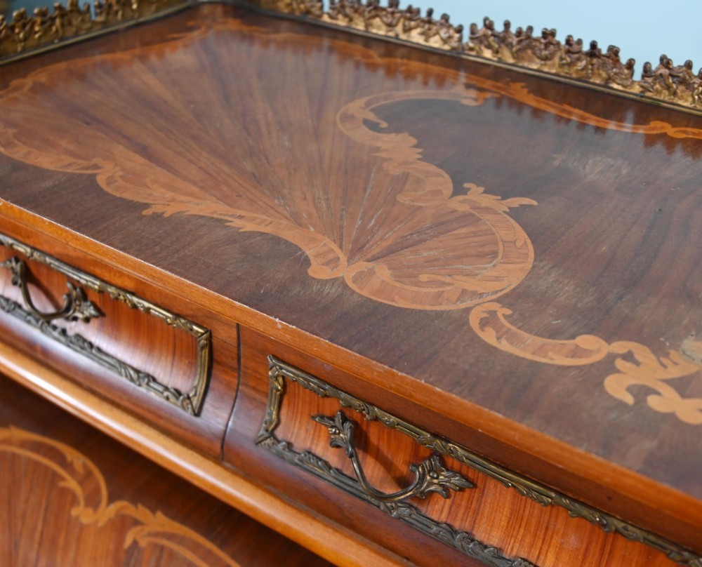 An antique French roll-top bureau featuring wood marquetry inlay, decorative brass mounts, cabriole legs, and drawers. View X