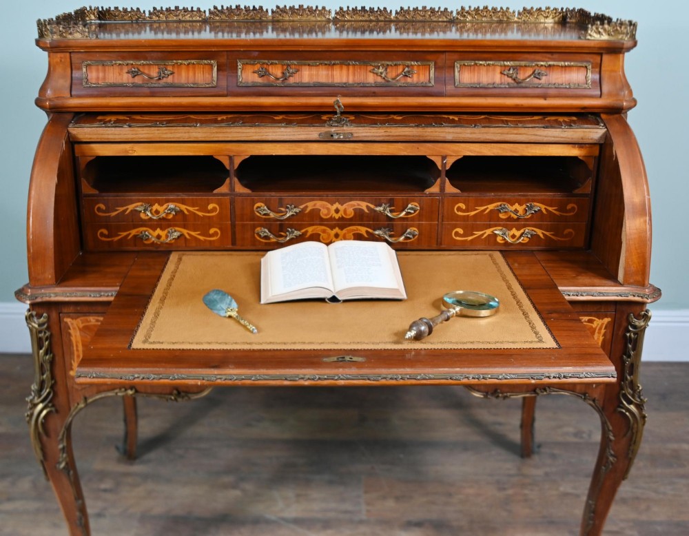 An antique French roll-top bureau featuring wood marquetry inlay, decorative brass mounts, cabriole legs, and drawers. View XII