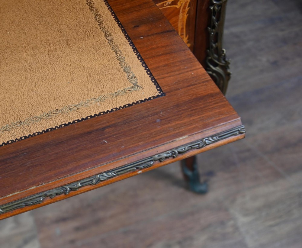 An antique French roll-top bureau featuring wood marquetry inlay, decorative brass mounts, cabriole legs, and drawers. View XIV