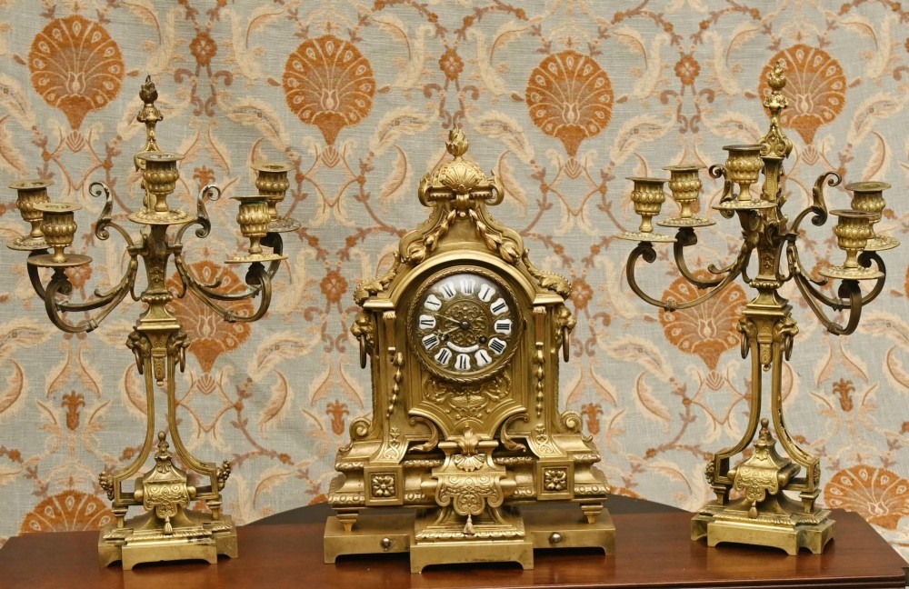 A 19th-century Louis XVI style gilt bronze clock garniture set comprising a central ornate mantel clock flanked by two matching five-light candelabras.